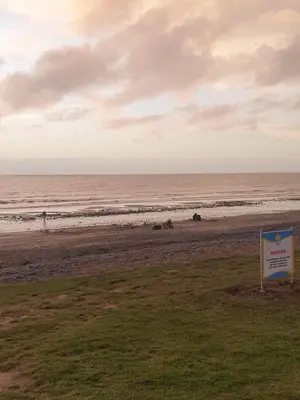 a sign on a beach with the ocean in the background at Premium 3 Bedroom Static Caravan with Sea Views Aber Bay in Aberystwyth