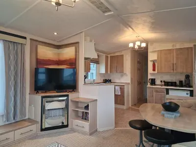 a living room with a tv and a kitchen with a table at Premium 3 Bedroom Static Caravan with Sea Views Aber Bay in Aberystwyth