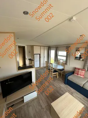 a living room with a tv and a couch and a table at Snowdon Summit 002 in Barmouth