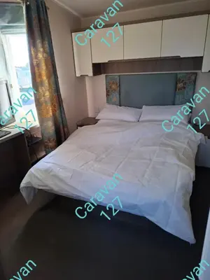 a large white bed in a bedroom with a window at Caravan 127 in Barmouth