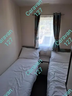 a small room with two beds and a window at Caravan 127 in Barmouth