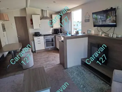 a kitchen and living room with a stove and a tv at Caravan 127 in Barmouth