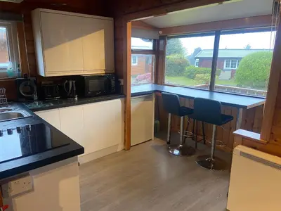 a kitchen with a counter and two stools in it at Log Cabin in Beautiful Snowdonia in Trawsfynydd