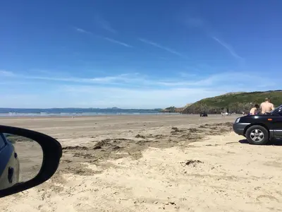 a car parked on a beach near the ocean at Log Cabin in Beautiful Snowdonia in Trawsfynydd