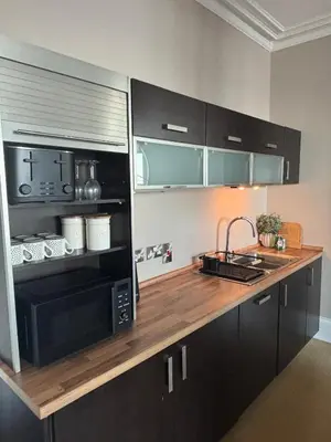 a kitchen with black cabinets and a microwave at Swn Y Mor 3 Aberystwyth in Aberystwyth