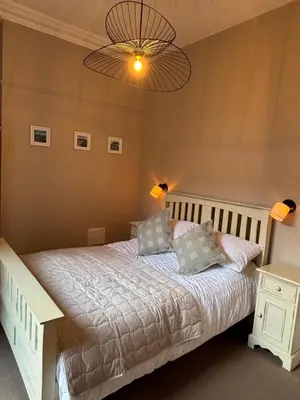 a bedroom with a bed and a chandelier at Swn Y Mor 3 Aberystwyth in Aberystwyth