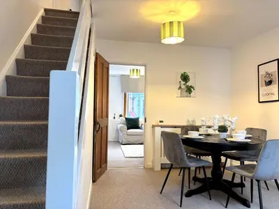 a dining room with a table and chairs and a staircase at 2 bedroom house 12mins walk to town in Shrewsbury