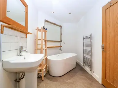 a bathroom with a tub and a sink and a mirror at The Swan in Hereford