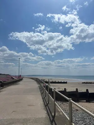 a walkway to the beach with a cloudy sky at The Woodlands Caravan in Bryn-glâs Station