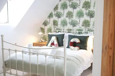 a bedroom with a white bed with trees on the wall at Abbey Cottages- Red Kite Lodge in Talley