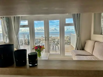 a living room with a couch and a view of the ocean at Dolphin View in Llanddwywe