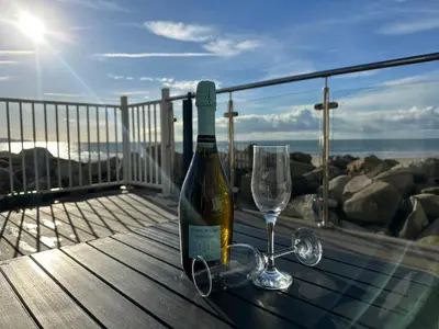 a bottle of wine and glasses on a table on a balcony at Dolphin View in Llanddwywe