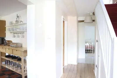 a kitchen with white walls and a wooden floor at Abbey Cottages- Heron House in Talley