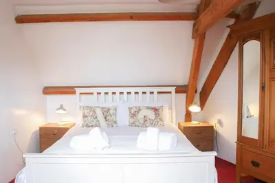 a bedroom with a white bed with two night stands at Abbey Cottages- Heron House in Talley