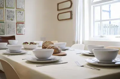 a table with white bowls and plates on it at Abbey Cottages- Heron House in Talley