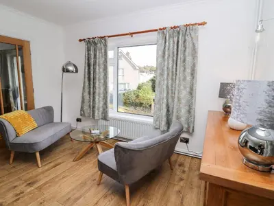 a living room with a chair and a table and a window at Ty Melyn in Aberystwyth