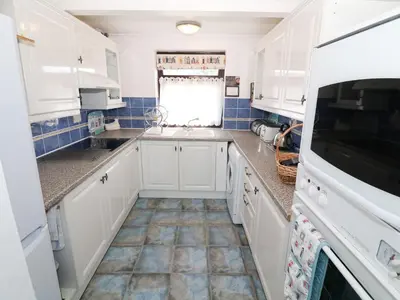 a kitchen with white cabinets and a tile floor at Goetra in Harlech