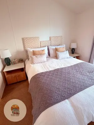 a bedroom with two beds with pillows and two lamps at Dune View Chalet in Ynys-lâs Station