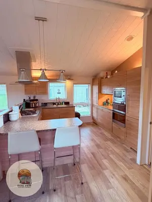 a kitchen with wooden cabinets and a table and chairs at Dune View Chalet in Ynys-lâs Station