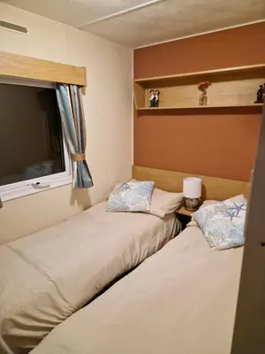 two beds in a small room with a window at Brynowen Holiday Park Borth in Borth