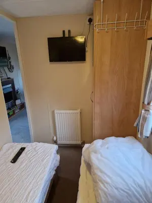 a bedroom with a bed and a tv on the wall at Brynowen Holiday Park Borth in Borth