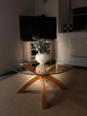 a glass table with a vase of flowers on top of it at Henllys Cottage in Corwen
