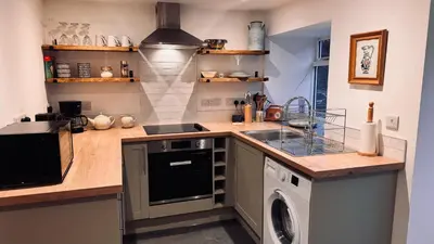 a kitchen with a sink and a washing machine at Henllys Cottage in Corwen