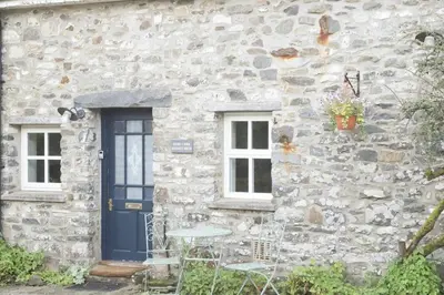 a stone house with a blue door and two windows at Abbey Cottages - Buzzards Watch in Talley