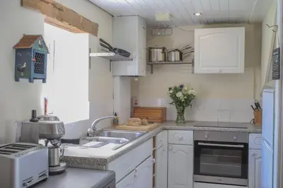 a kitchen with white cabinets and a sink at Abbey Cottages - Buzzards Watch in Talley