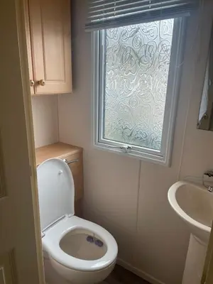 a bathroom with a toilet and a sink and a window at Family 3 Bedroom Caravan at Clarach Bay in Aberystwyth