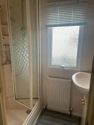a bathroom with a shower and a sink and a window at Family 3 Bedroom Caravan at Clarach Bay in Aberystwyth