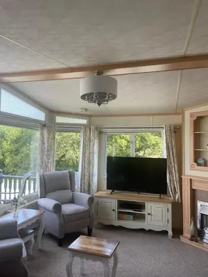 a living room with a television and a couch and chairs at Family 3 Bedroom Caravan at Clarach Bay in Aberystwyth