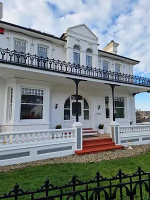 a white house with a porch and a fence at Hazeldene Guest House in Aberaeron