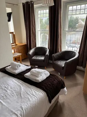 a hotel room with a bed and two chairs and a window at Hazeldene Guest House in Aberaeron