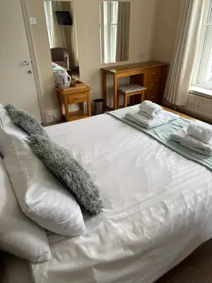 a white bed with two towels on top of it at Hazeldene Guest House in Aberaeron