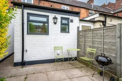 a patio with two chairs and a table and a grill at Quaint home with log burner in peaceful cul-de-sac in Shrewsbury