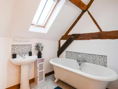 a bathroom with a white tub and a sink at The Byre At Woodgate Farm in Church Stretton