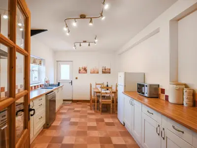 a kitchen with white cabinets and a table in it at The Byre At Woodgate Farm in Church Stretton