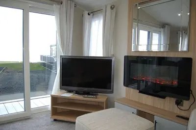 a living room with a television and a large window at Seaview Caravan f17 at Neptune Park, Tywyn in Tywyn