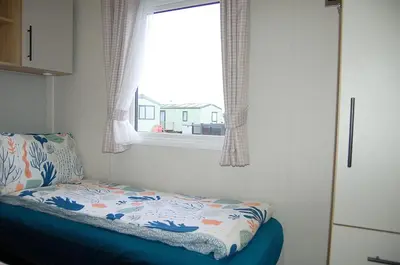 a bedroom with a bed in front of a window at Seaview Caravan f17 at Neptune Park, Tywyn in Tywyn