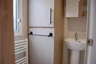 a small bathroom with a sink and a refrigerator at Seaview Caravan f17 at Neptune Park, Tywyn in Tywyn