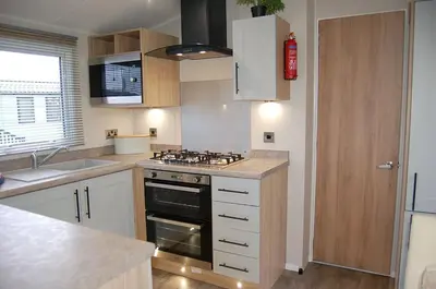 a kitchen with a stove top oven next to a sink at Seaview Caravan f17 at Neptune Park, Tywyn in Tywyn