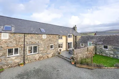 an exterior view of a stone house with a driveway at Melin-Bennar in Dyffryn