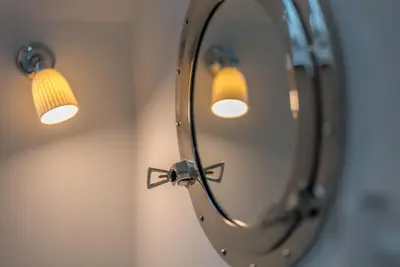 a mirror with a light on a wall at Melin-Bennar in Dyffryn