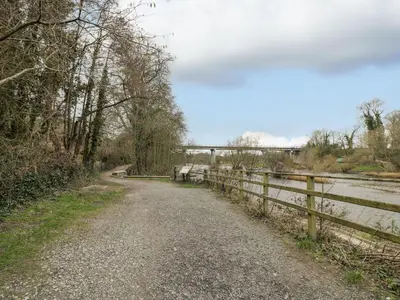 a dirt road next to a fence next to a river at Cariad Cottage in Hereford