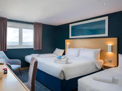 a hotel room with two beds and a desk at Travelodge Oswestry in Oswestry