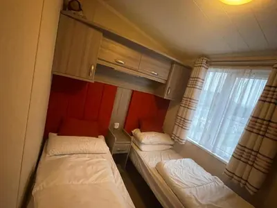 two beds in a small room with a window at Sea and Bay Viev Luxury Lodge in Clarach bay in Aberystwyth