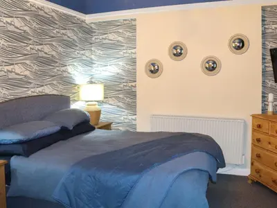 a bedroom with a blue bed and a wall at Brig Y Don in Borth