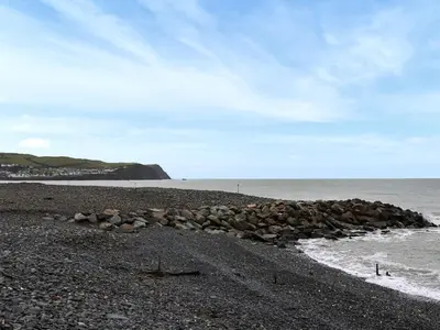 a group of rocks on a beach next to the ocean at Brig Y Don in Borth