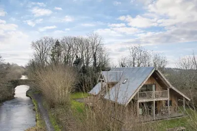 a house with a metal roof next to a river at Finest Retreats - Canal Central in Ball
